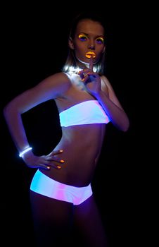 Disco sexy girl with glow make-up silence sign dance in ultraviolet light