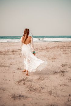 Model in boho style in a white long dress and silver jewelry on the beach. Her hair is braided, and there are many bracelets on her arms