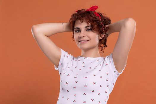 Attractive young girl with a beautiful smile one hundred and one brick-colored background. White blouse with cherry pattern.