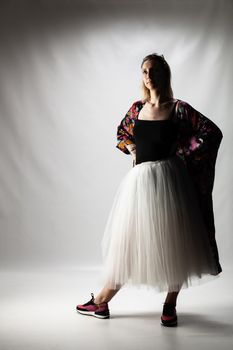 casual ballerina with a white dress black top amd shoes standing on gray background