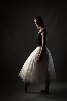 ballerina with a white dress and black top posing on gray background