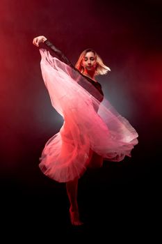 ballerina with a white dress and black top posing on red smoke background.