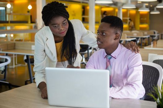 Smiling young african american professional businessman and businesswoman working on laptop.