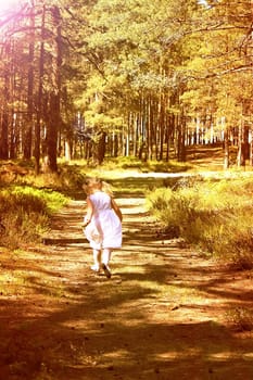 Little girl running in sunlight in the autumn park