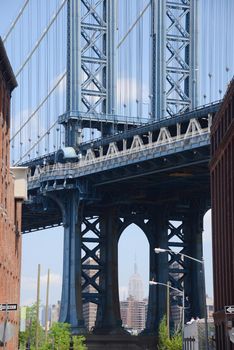 east tower of manhattan bridge framed with old building in brooklyn and empire state