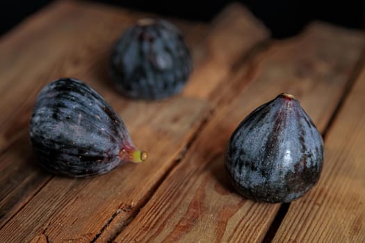 Fresh purple figs on a wooden background from old boards. Raw exotic figs. Low key
