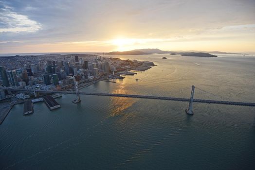 an aerial view of bay bridge near san francisco downtown during sunset, taken from a helicopter 