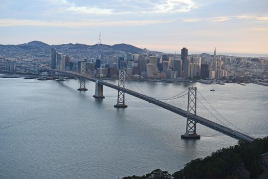 an aerial view of bay bridge near san francisco downtown during sunset, taken from a helicopter 