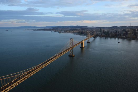 an aerial view of bay bridge near san francisco downtown during sunset, taken from a helicopter 