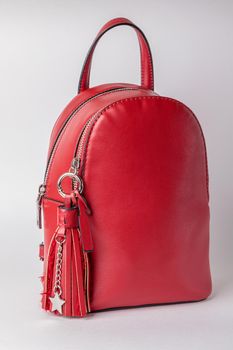 Fashionable female backpack on a white background. Leather red backpack with an iron zipper. Close-up.