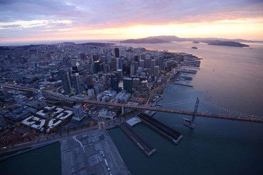 an aerial view of bay bridge near san francisco downtown during sunset, taken from a helicopter 