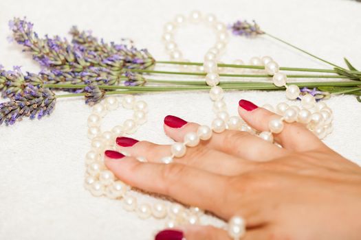 Hands of a woman with red nail polish posed by an esthetician