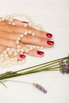 Hands of a woman with red nail polish posed by an esthetician