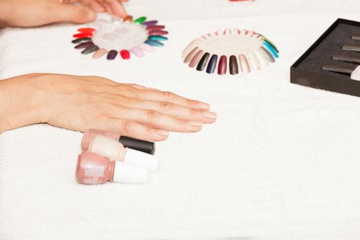 Hands of a woman who chooses the color of her nail polish