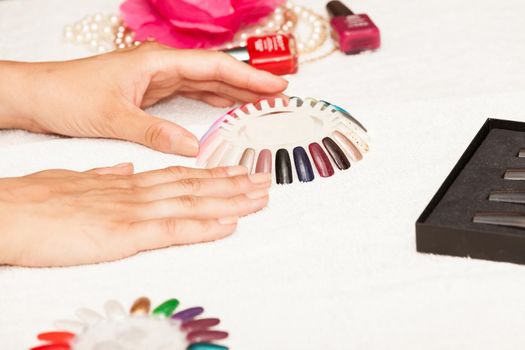 Hands of a woman who chooses the color of her nail polish