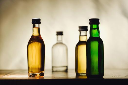 different alcohol bottles are on the table on a light background.