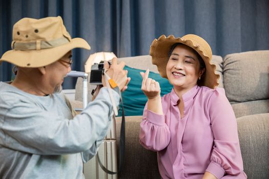 Travel and tourism. Asian couple old senior marry retired couple smiling taking photo by camera during luggage suitcase arranging for travel, Happy mature retired couple photography weekend holiday