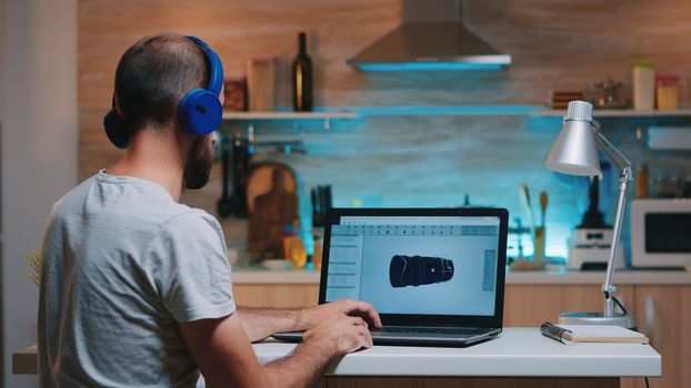 Remote man architect working from home at laptop on modern cad program overtime wearing headset. Industrial employee studying prototype idea on computer showing cad software on device display