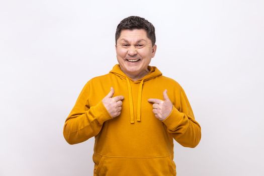 Proud satisfied man pointing fingers on himself and looking at camera with toothy smile, extremely satisfied, wearing urban style hoodie. Indoor studio shot isolated on white background.
