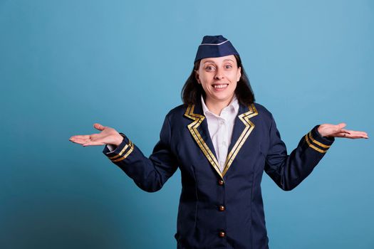 Young confused flight attendant shrugging shoulders, showing unsure gesture, looking upwards. Air hostess with doubtful facial expression, puzzled stewardess, uncertain sign