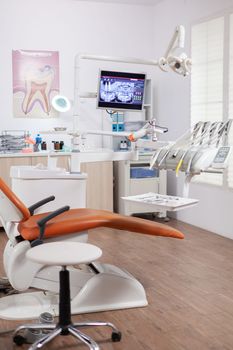 Interior of empty operating room in dental clinic. Stomatology cabinet with nobody in it and orange equipment for oral treatment.