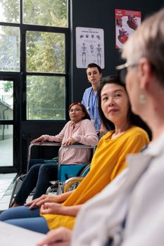 Nurse helping woman with physical injury to attend rehabilitation appointment in hospital waiting area, Senior doctor talking with asian patient explaining disease diagnosis. Medicine concept