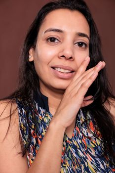 Indian woman whispering, telling secret, gossiping, holding palm near mouth portrait. Rumor, communication, news concept, lady gossiping, looking at camera, front close view