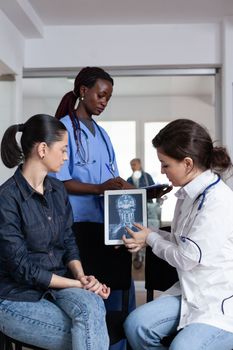 Laboratory doctor examining inside body images of patient in hospital consultation. Sick woman receiving illness diagnosis in clinical tower. African american general practitioner interpreting x rays.