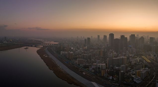 Hazy sunrise over high rise buildings in sprawling city next to river. High quality photo