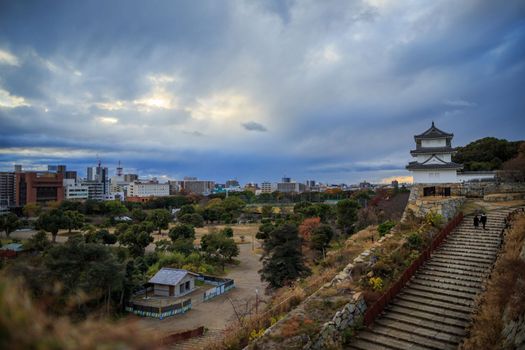 Dramatic sky over stairs to Japanese castle tower and city skyline. High quality photo