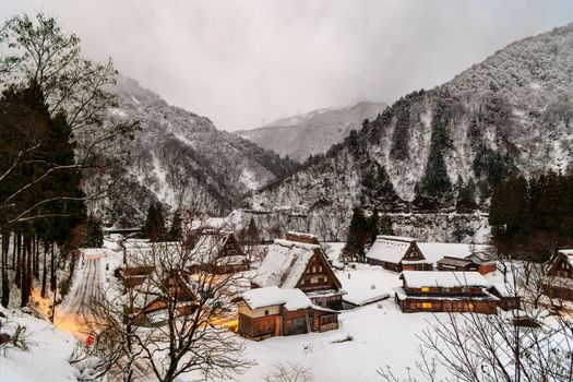 Lights on in snowy UNESCO World Heritage village in mountain landscape at dawn. High quality photo