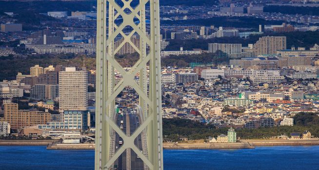 Akashi Kaikyo suspension bridge with light afternoon traffic and residential apartments in sprawling Maiko