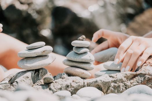 Balanced Pebbles Pyramid on the Beach on Sunny Day and Clear Sky at Sunset. Blue Sea on Background Selective focus, zen stones on sea beach, meditation, spa, harmony, calm, balance concept.