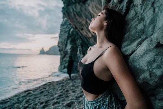 Portrait of cheerful female climber ascending a rock. The athlete girl trains in nature. Woman overcomes difficult climbing route.