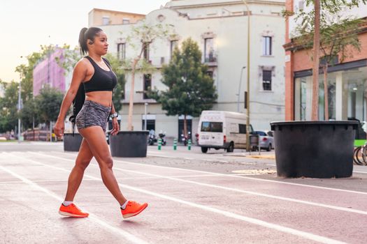 latina sportswoman walking with a backpack on a city athletics track, urban sports and healthy lifestyle concept, copy space for text