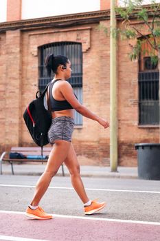 latin sportswoman walking with a backpack in the city, urban sport and healthy lifestyle concept