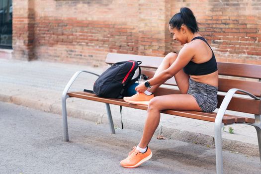 young sportswoman lacing up her running shoes before her workout, urban sport and healthy lifestyle concept, copy space for text