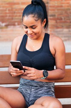 young sportswoman using her mobile phone before her workout, urban sport and healthy lifestyle concept
