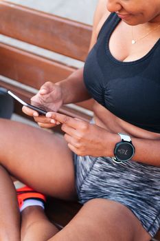 unrecognizable sportswoman using her mobile phone before her workout, urban sport and healthy lifestyle concept