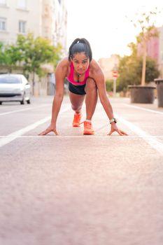 female athlete ready to run at the starting line of the city's athletics track, concept of urban sport and healthy lifestyle, copy space for text