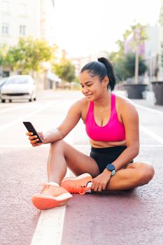 female athlete using her mobile phone sitting on the city athletics track after her workout, concept of sport and healthy life style, copy space for text