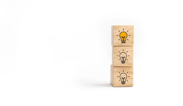 Wooden cube block tower with light bulb icon on white background. Concept creative idea and innovation.