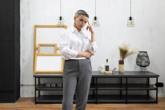 strong mature woman designer in white shirt and gray pants inside.