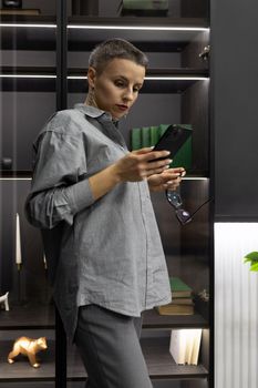 Strong woman on in a gray interior with a phone in her hands.