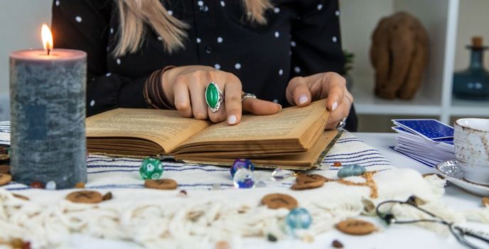 Woman fortune teller reads a book of spells. Selective focus. People.