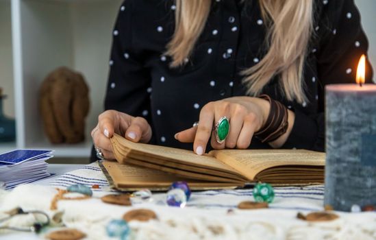 Woman fortune teller reads a book of spells. Selective focus. People.