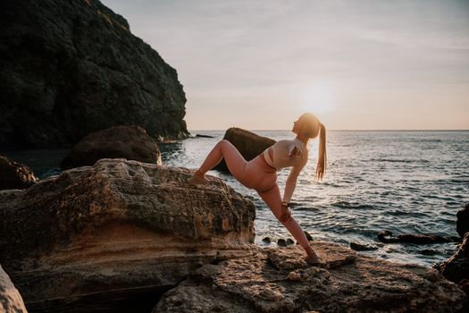 Young woman with black hair, fitness instructor in pink sports leggings and tops, doing pilates on yoga mat with magic pilates ring by the sea on the beach. Female fitness daily yoga concept