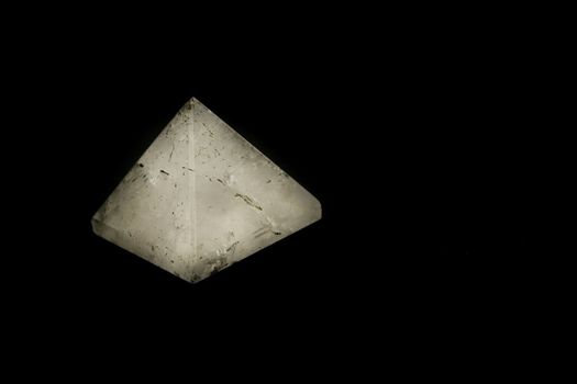 white quartz pyramid illuminated on black background