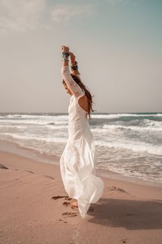 Model in boho style in a white long dress and silver jewelry on the beach. Her hair is braided, and there are many bracelets on her arms