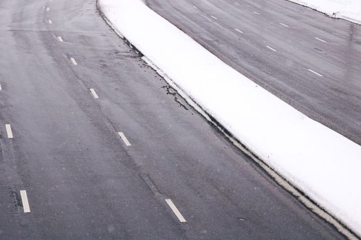 A wide road in the snow in winter close up